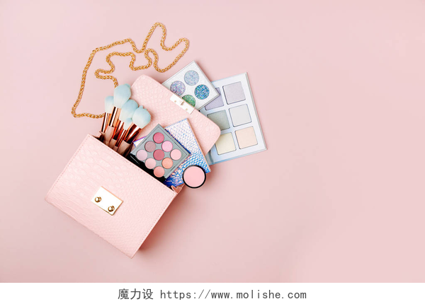 粉色的桌子上摆放着一个粉色包包化妆品从化妆袋流动在柔和的粉红色的背景